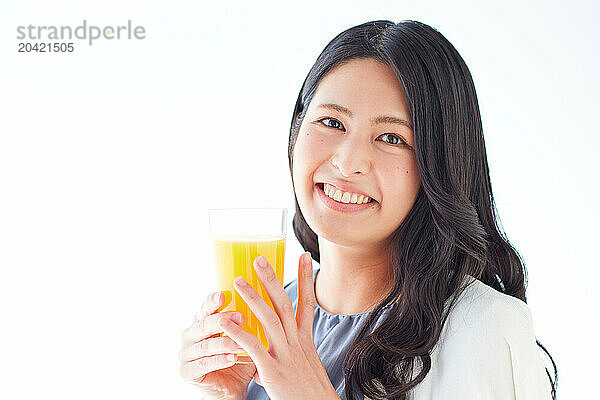 Japanese woman holding a glass of orange juice