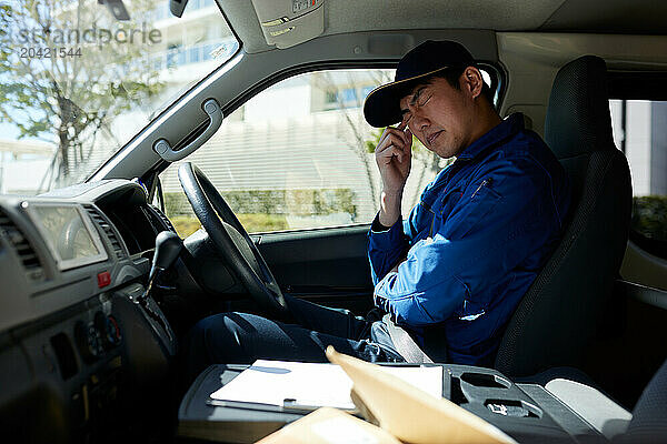 Japanese delivery man sitting in the driver seat