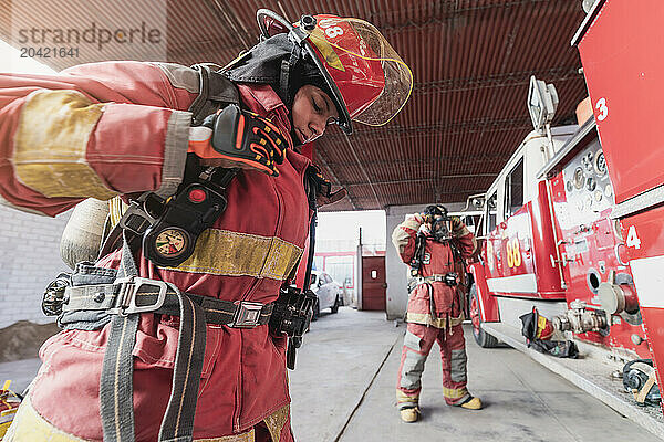 Female firefighter with workwear working at fire engine