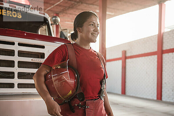 Portrait of happy female firefighter standing at fire station