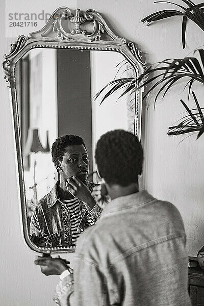 young short haired african young woman make up in a mirror