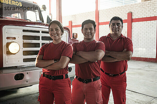 Team of female and male firefighters smiling standing at fire station