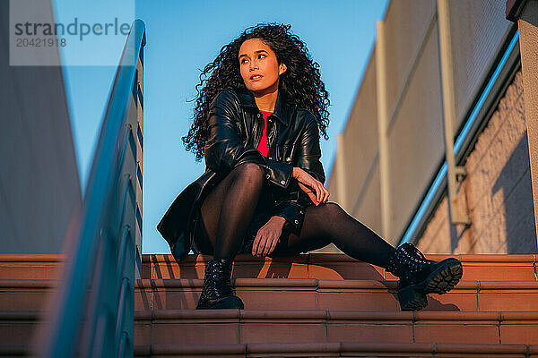 Curly-haired woman sitting on steps of building