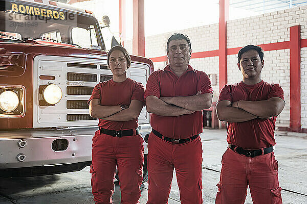 Team of female and male firefighters smiling standing at fire station