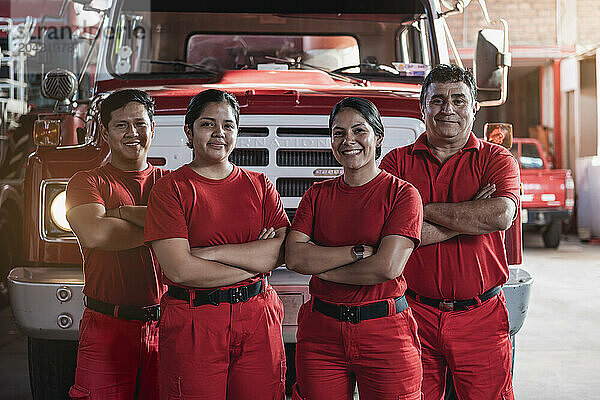 Smiling team of male and female firefighters at fire station