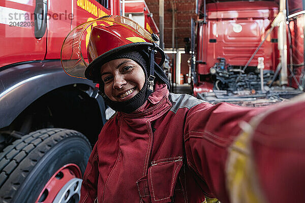 Happy female firefighter taking selfie at the fire station