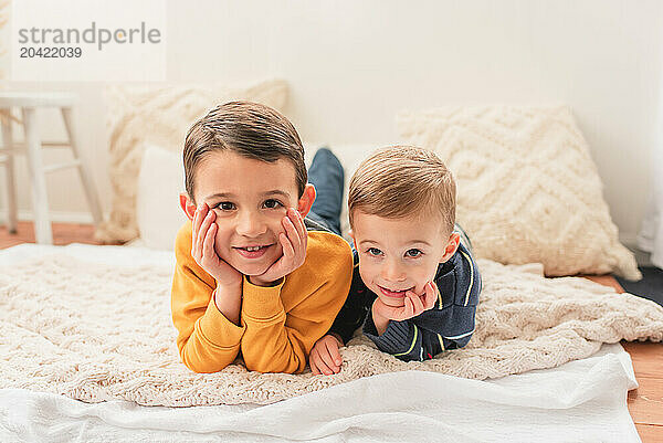 Two brothers laying on blankets on belly and smiling at camera