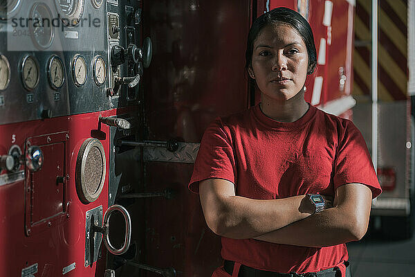 Portrait of female firefighter standing against fire engine