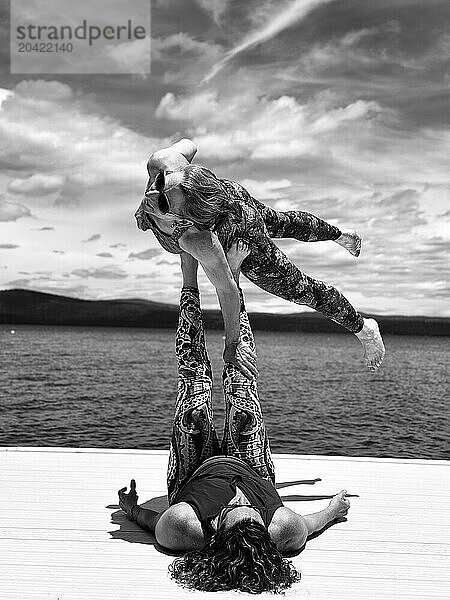 Acroyoga duo flying above a lake