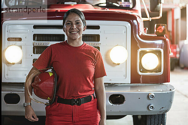 Portrait of smiling female firefighter standing at fire station