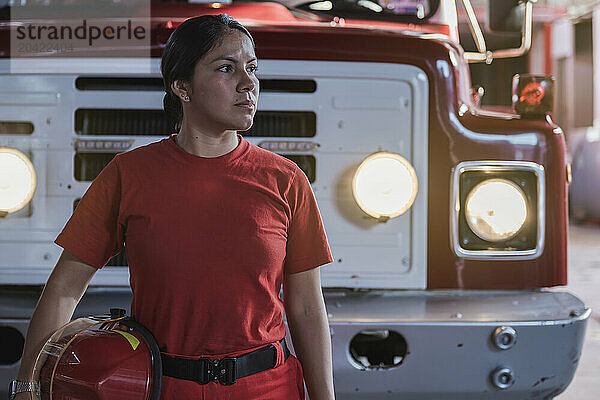 Portrait of female firefighter standing at fire station