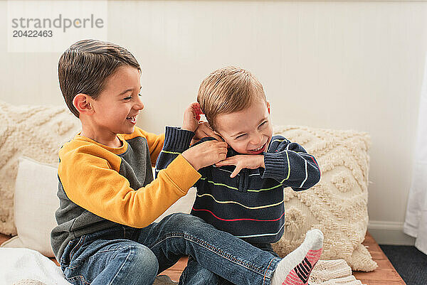 Cheerful brothers playing together and tickling while sitting at home