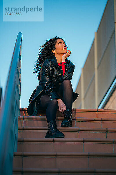 Curly-haired woman sitting on steps of building