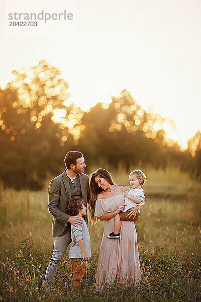 Family of four enjoying a golden sunset in a grassy field  inter