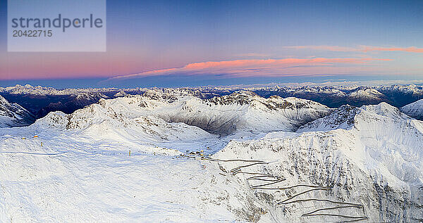 Aerial view of winding snowy mountain road at Stelvio Pass at sunrise