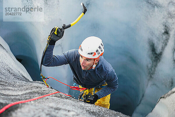 Young man ice climbing up a crevasse on an Icelandic glacier