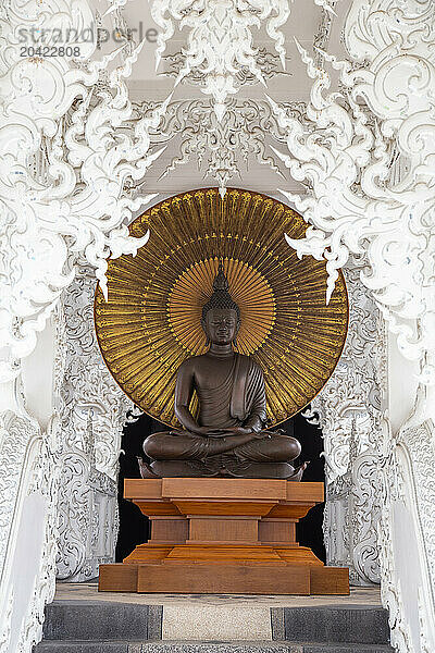 Golden buddha statue surrounded by white decorations