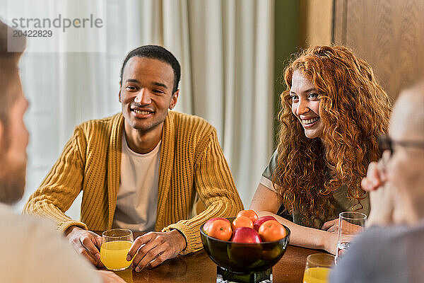 multiracial friends hanging out together at home sitting and chatting