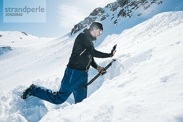 Man creating snow profile for avalanche control on snowy mountain