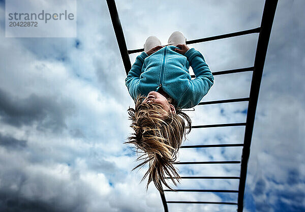 Young child hanging from monkey bars school playground