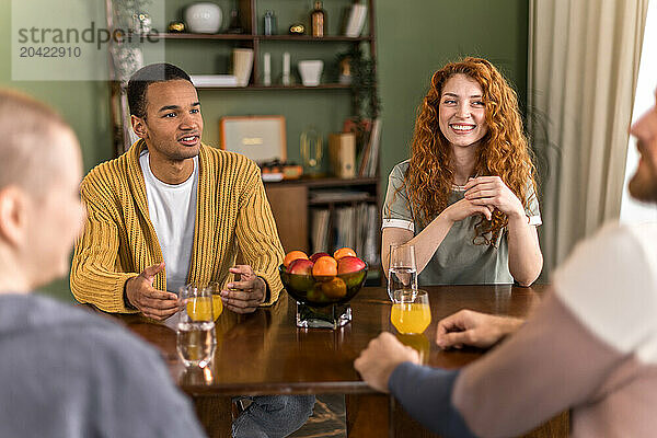 multiracial friends hanging out together at home sitting and chatting