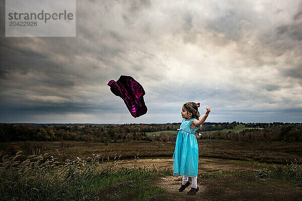 Little girl playing super hero outdoors in summer