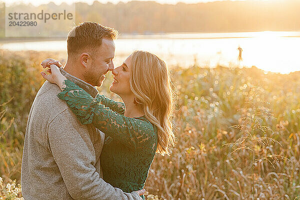 Romantic couple embracing in field at sunset