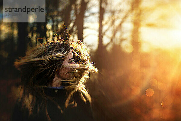 Beautiful teen girl flipping hair in golden sunlight