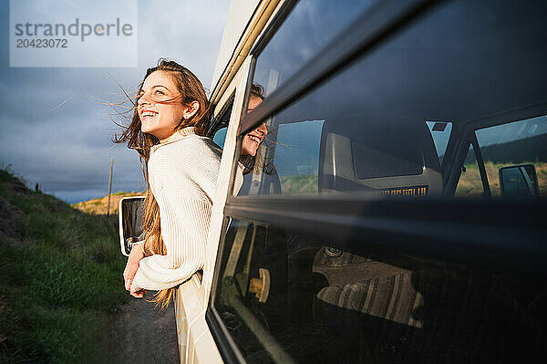 Happy young woman standing near door in driver seat