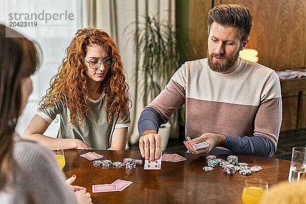 enjoying friends sitting at table and play card games