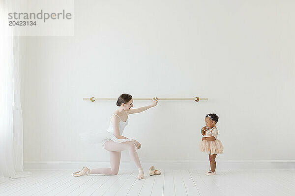 Ballerina shows little girl in tutu the studio ballet barre