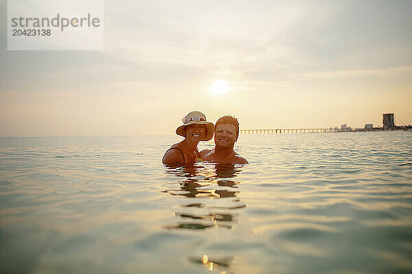 Couple embracing in ocean at sunset  serene with smiles