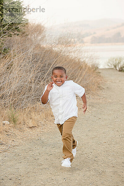 Boy running on a path outside smiling