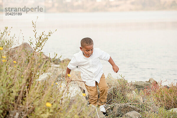 Boy exploring on the rocks by the water