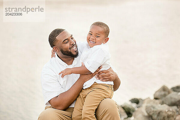 Laughing father and son outside by the water