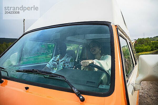 Cheerful diverse couple and woman driving van in daylight