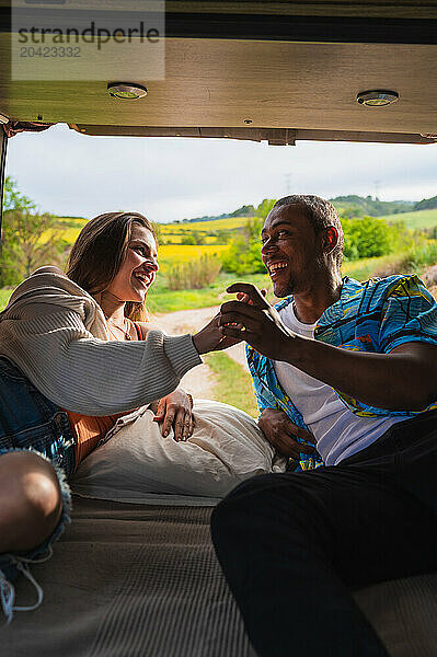 Happy diverse couple lying in van and spending time together