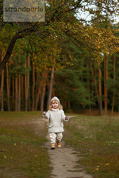 happy little girl walks through the autumn forest and plays