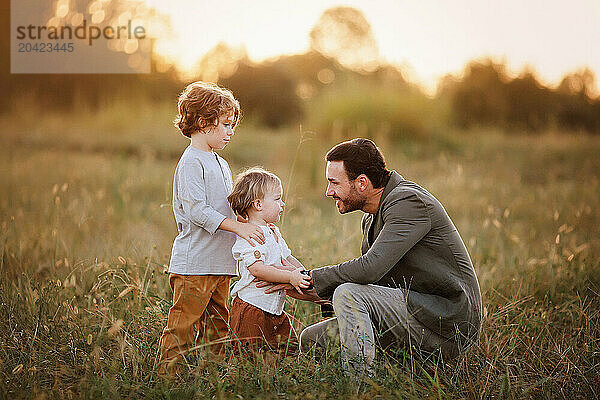 Father kneeling in a grassy field  interacting warmly with his t