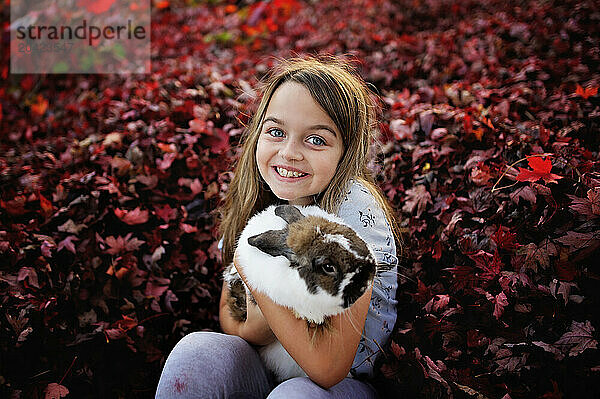 Happy little girl holding Holland Lop rabbit