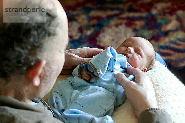 Grandfather gently holding a sleeping newborn at home