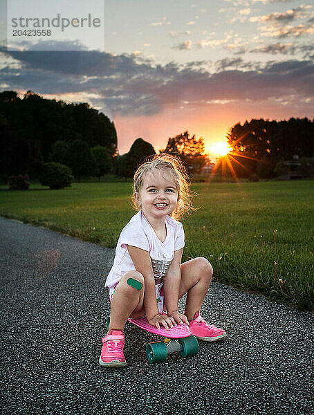 Beautiful happy girl riding skateboard with bandaid on knee