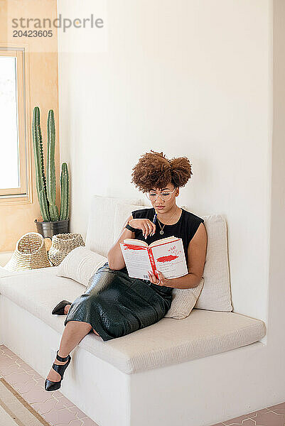 Black women sitting on couch reading a book