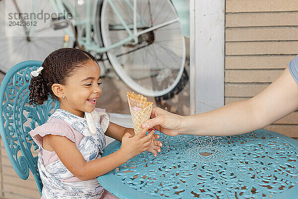 mom hands ice cream cone to daughter in cute downtown