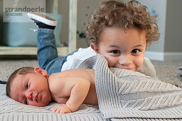 toddler brother cuddling newborn on soft blanket