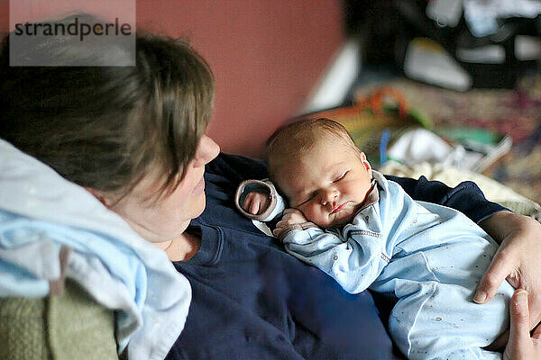 Mother holding her sleeping newborn baby at home