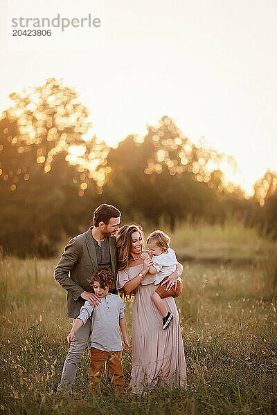 Family of four enjoying a golden sunset in a grassy field  inter