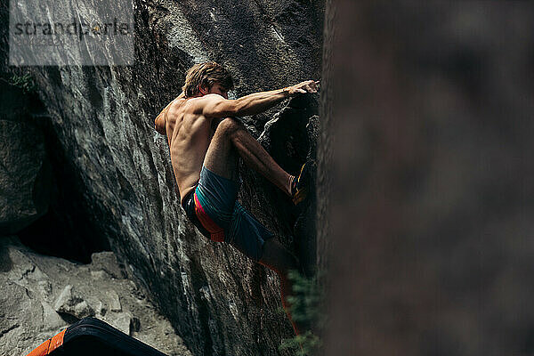 Muscular climber on a boulder in Magic Wood  Switzerland