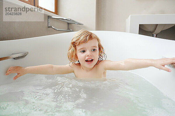 A little smiling girl takes a bath