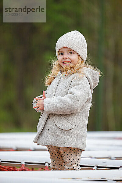 Portrait of a small smiling girl on a playground in a city park